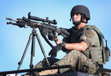 Click on image to see full-sized version One of the heavily militarised police in Ferguson points his military sniper rifle at peaceful protesters